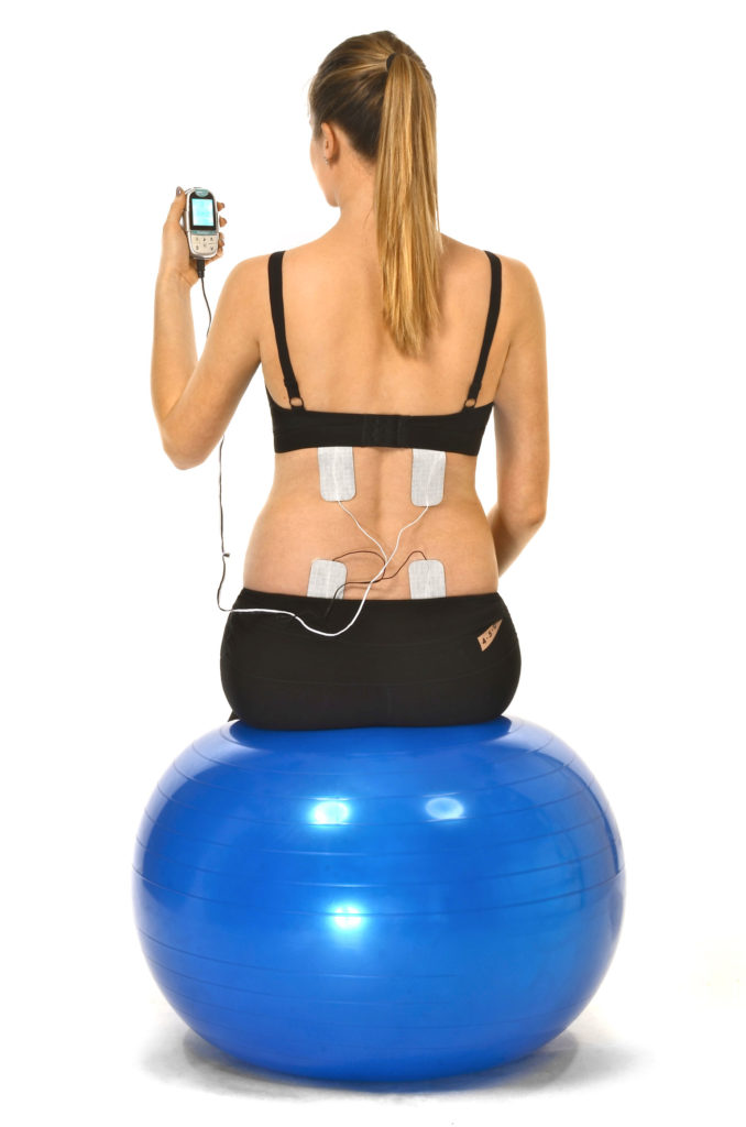 women on exercise ball with electrode pads on back